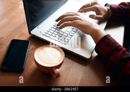young man in stylish red checked shirt earning money online, close up cropped photo, man making up a project, programmer dowloading anti viarus system Stock Photo