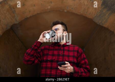 Outdoor portrait of stylish guy using his mobile phone, making a phone call, having coffee break. low view, business man. coffee lover Stock Photo