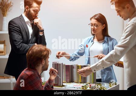 hardworking team of achitects having a conversation in the office, measuting a model with a ruler . close up photo, four architects brainstorming, usi Stock Photo