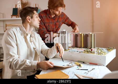 young handsome men working on architectural urban project, planning construction, team is keen on new building plan in the office, close up side view Stock Photo