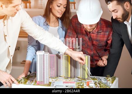 ambitious colleagues collaborating and discussing project plans, learning the model of new neighbourhood Stock Photo