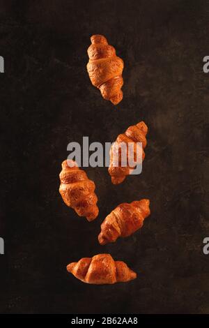 Croissants flying on dark background. Levitation scene. Stock Photo