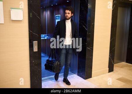 young handsome man in black gloves holding a leather black bag leaving the lift. full length photo, strange man going to blow up the office building , Stock Photo