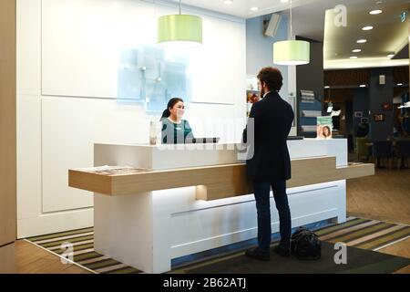 serious female receptionist worker standing at hotel counter, close up photo.Welcome to the hotel. receptionist and client standing at the registratio Stock Photo