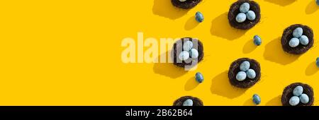 Blue textured colored Easter eggs and bird nest on a bright yellow holiday background backdrop. Spring holiday concept. Copyspace. Flat lay. Top view. Stock Photo