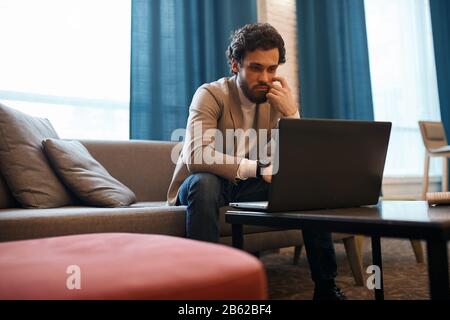 young man with bearded concentrated on using laptop, close up photo. young guy earning money online, watching film, movie Stock Photo