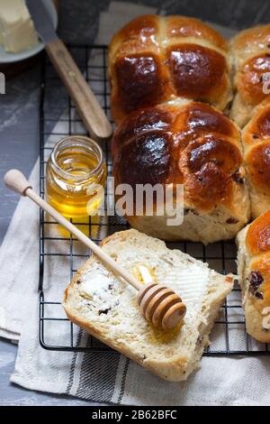 Traditional hot cross buns with honey and butter on a concrete background. Stock Photo