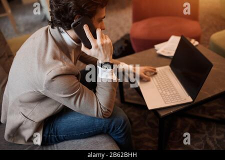young serious man using the laptop, having a chat with customers, selling goods online, consulting clients. close up side view photo Stock Photo