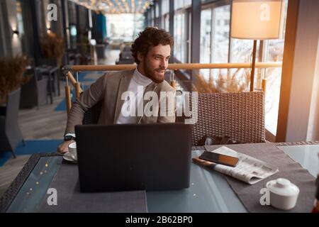 handsome manager working at the cafe, having a rest, looking for inspiration for a new project, close up side view photo, smiling happy man enjoying s Stock Photo