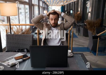 puzzled man solving business problem, guy cannot fix the computer, man reading unhappy news, information Stock Photo