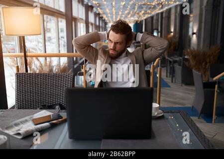 frustrated unhappy sad man isn't satisfied with company work, guy solving problems, man is angry as his laptos has broken, negative feeling and eemoti Stock Photo