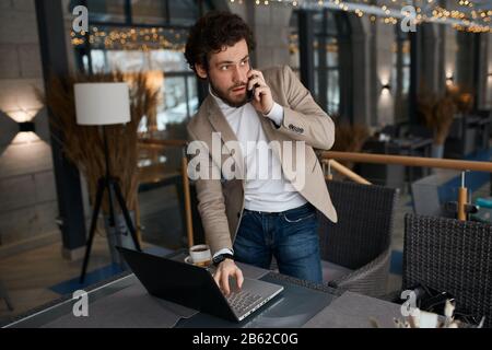 handsome businessman having a phone conversation and working on a laptop computer, close up photo. lifestyle, free time, spare time Stock Photo