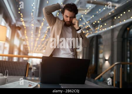 serious puzzled unhappy sad guy having problems with computer, scratching his head, talking with friend, close up photo Stock Photo