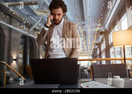 bearded man fixing computer, downloading antuvirus system, close up phto. man talking with a client, customer. Stock Photo
