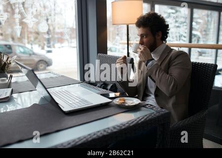 young fashion man drinking tea, having coffee break in the cafe. close up side view photo. Stock Photo
