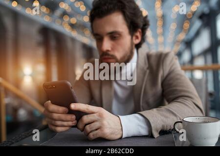 focus on the smart phone blurred image, guy doing shopping online, close up photo. man concentrated on working with gadget Stock Photo