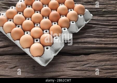 Close-up view of raw chicken eggs in egg box on old brown wooden background Stock Photo