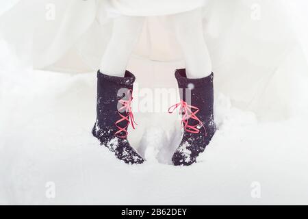 A closeup of the feet of the bride in felt boots on snow. Accessories for a stylized Russian wedding. Stock Photo
