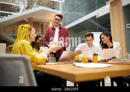 young business people sharing creative ideas , plans, designers discussing project, text, report indoors. creativity concept Stock Photo