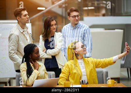 cheerful pleasant attractive woman trying to catch the moment, taking pictures with her co-workers. close up photo Stock Photo