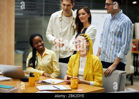 positive cheerful young fashion people laughing, having fun, spending great time in the office with modern interior. close up side view photo Stock Photo