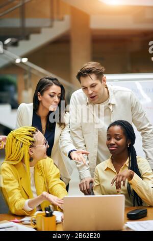 young designers choosing furniture for office, buying goods online, doing shopping together, working with laptop in the office Stock Photo