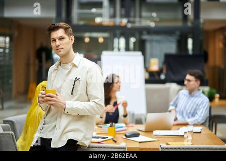 handsome man leaning on the desk and looking at the camera. close up photo. copy space. blurred background Stock Photo
