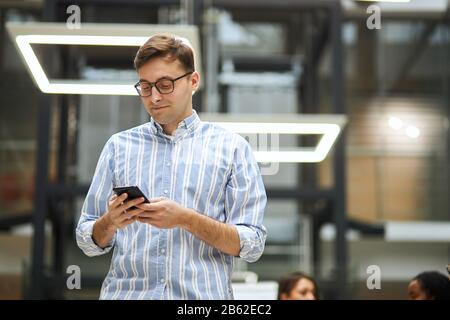 young clever man in glasses working with cell phone. low angle view . gadget, guy briwsing the net, download files, documents, photos, music, looking Stock Photo