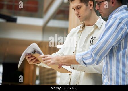 handsome men analyzing document, preparing a report for meeting, close up side view photo. man in white stylish shirt holding important documents and Stock Photo