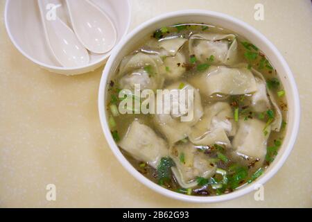 Top view of a traditional Chinese dumplings soup, with scallion, in a white bowl Stock Photo