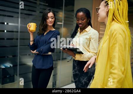 colleagues discussing something , afro woman checking the comapny's work, african woman writing her remarks, observation, giving advice, recommendatio Stock Photo