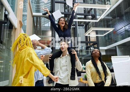 funny business team riding their successful talented leader on the shoulders, congratulating themselves, rejoicing at success.positive mood , atmossph Stock Photo