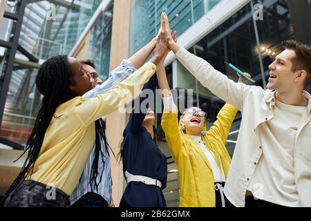 young funny emoloyees screaming, rejoicing at fist good results of their company. low angle view Stock Photo