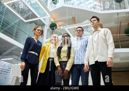 young attractive office workers posing to the camera, having free time, looking at the camera . spare time, lifestyle, job, profession. low view Stock Photo