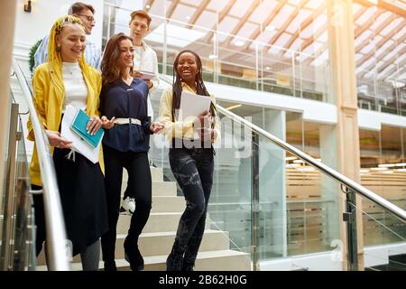 cheerful smiling positive colleagues having fun while walking in the office, copy space.coworkers telling jokes to each other Stock Photo