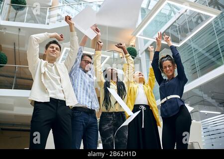young active business people standing in the offices, throwing sheets for work after finishing work in meeting room.we did it Stock Photo