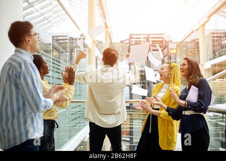 business people supporting crazy male colleague. back view photo Stock Photo