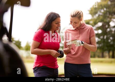 Two Women Playing Golf Marking Scorecard With  Buggy In Foreground Stock Photo