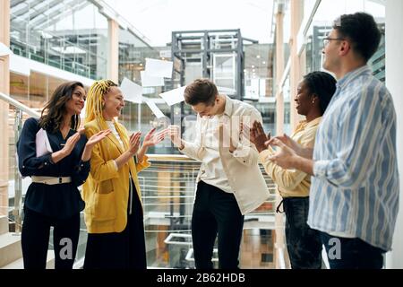 young men and women rejoicing at progress in deal, hurra. look of childish delight ,team shouting for joy Stock Photo