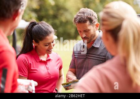 Group Of Male And Female Golfers Marking Scorecard On Course Stock Photo