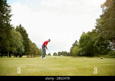 Mature Male Golfer Preparing To Hit Tee Shot Along Fairway With Driver Stock Photo