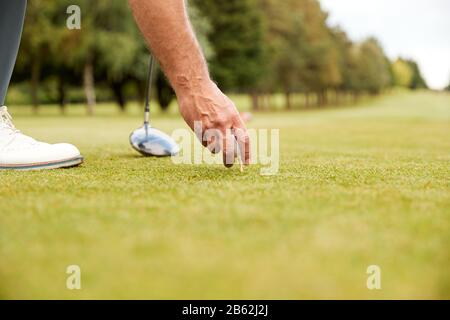 Close Up Of Mature Male Golfer Preparing To Hit Tee Shot Along Fairway With Driver Stock Photo