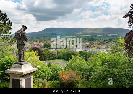 The Clitheroe war memorial faces east. The statue depicts a Grenadier Guard in battle order with cap, bowing his head, with Pendle hill in the distance. Stock Photo