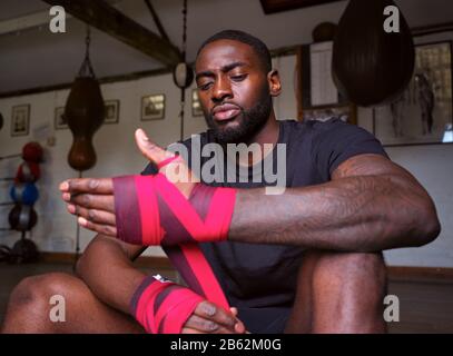 Male Boxer Training In Gym Wraps On Hands Standing Next To Punching Bag Stock Photo
