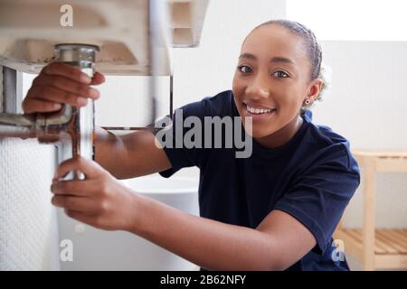 Portrait Of Female Plumber Working To Fix Leaking Sink In Home Bathroom Stock Photo
