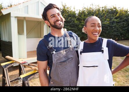 Couple Taking A Break From Building Outdoor Summerhouse In Garden Stock Photo