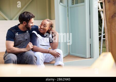 Couple Taking A Break From Building Outdoor Summerhouse In Garden Stock Photo