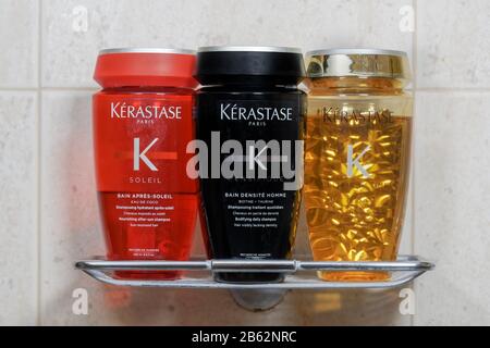 Kerastase Paris hair shampoo bottles closeup on bath stand. 3 different hair care shampoos, Solei, Densifique and Elixir Ultime on bathroom holder. Stock Photo