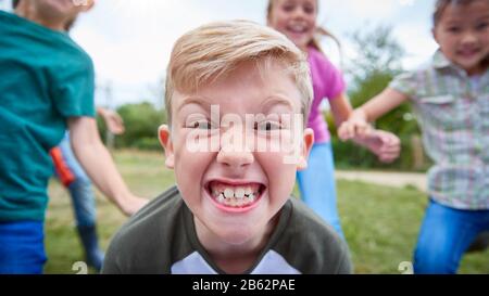 Portrait Of Children On Outdoor Activity Camping Trip Pulling Faces Having Fun Playing Game Together Stock Photo