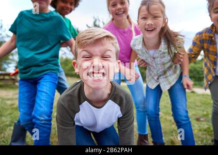 Portrait Of Children On Outdoor Activity Camping Trip Pulling Faces Having Fun Playing Game Together Stock Photo